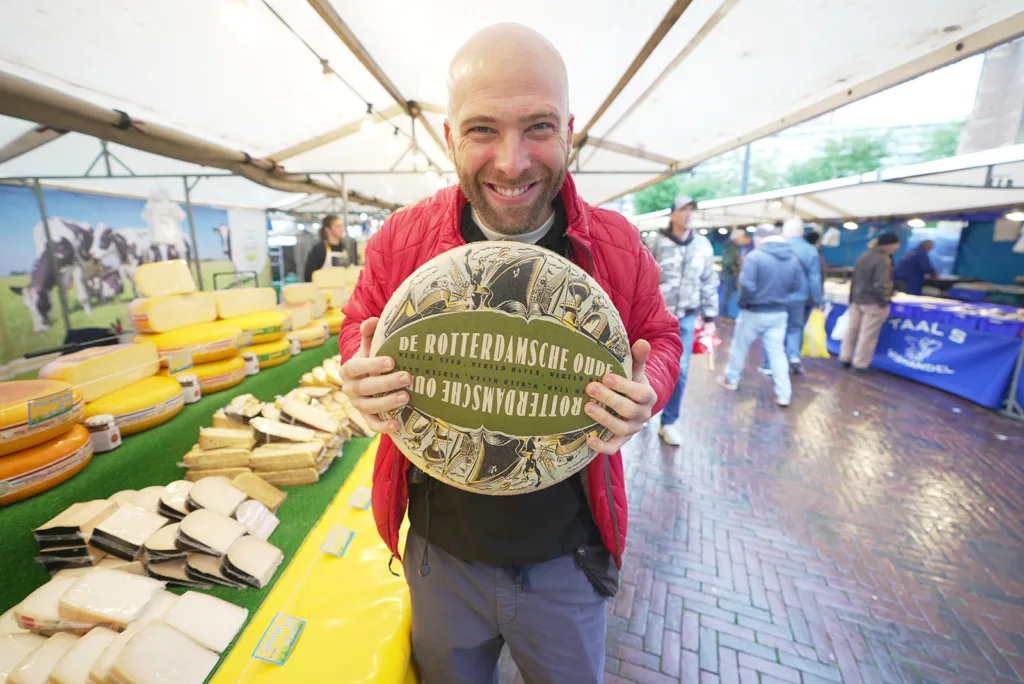 Me holding a wheel of cheese at a market in Rotterdam, the Netherlands, another great spot to learn the Dutch language | Davidsbeenhere