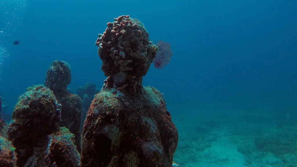 Underwater sculptures off the coast of Cancun, Mexico, with coral and sea plants growing on them | Davidsbeenhere