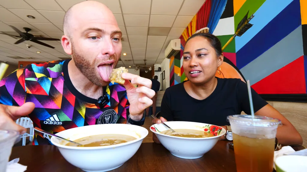 David Hoffmann eats a hearty piece of meat from his soup while his guide Stacy watches during his Caribbean food tour of Georgetown, Guyana | Davidsbeenhere