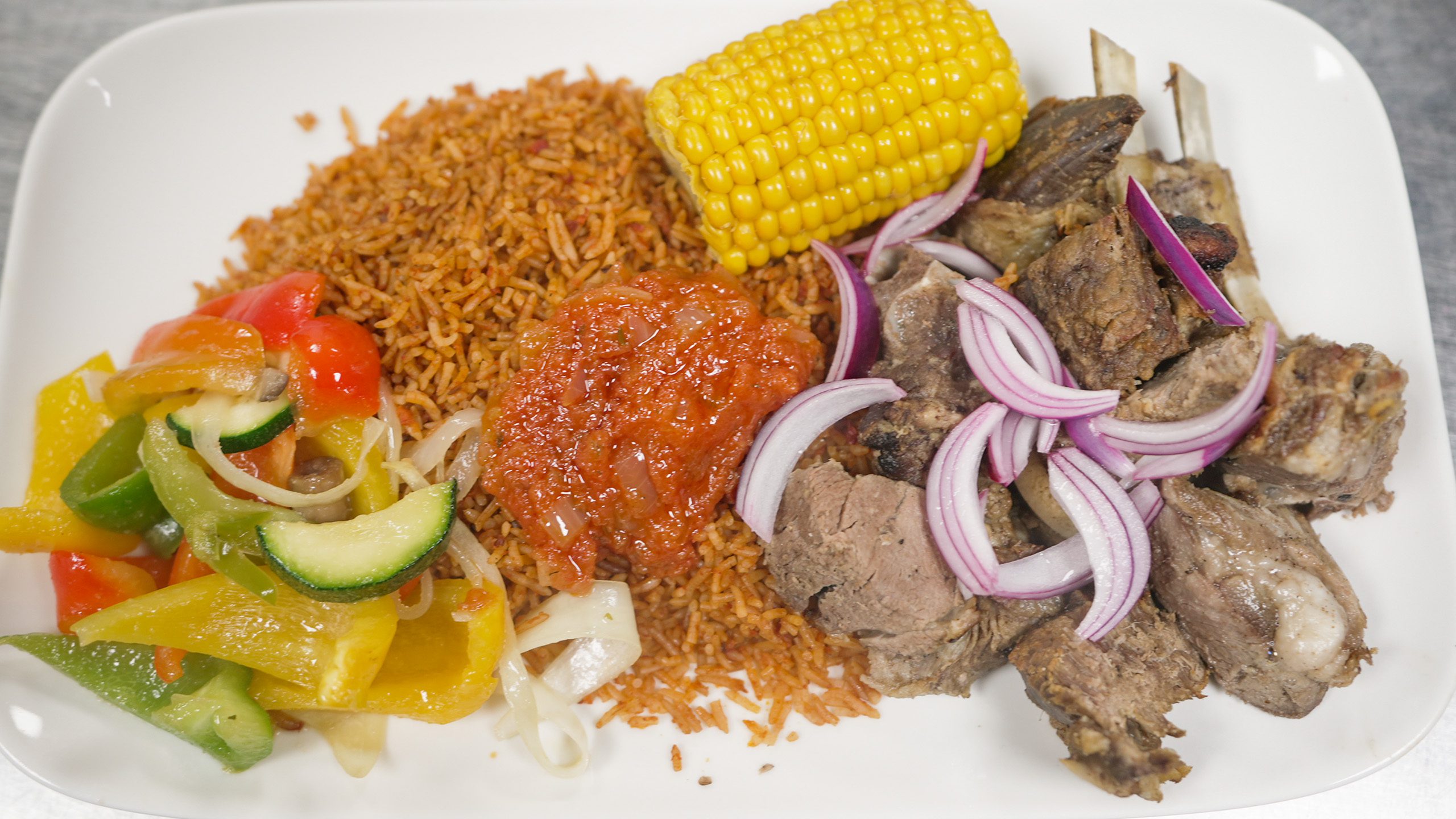 West African jollof rice, goat meat, corn, and salad in Amsterdam, the Netherlands | Davidsbeenhere